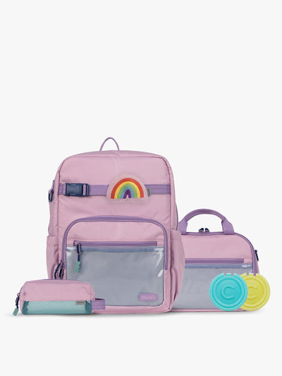 CALPAK Kids Collection Large Kids Backpack Bundle in pink lavender Orchid Pink that includes Kids Lunch Bag, Kids Pencil Case, Rainbow Pluffy Bag Charm, and Set of 2 Ice Packs in a kid's room; BCKL5000-ORCHID-PINK view 1